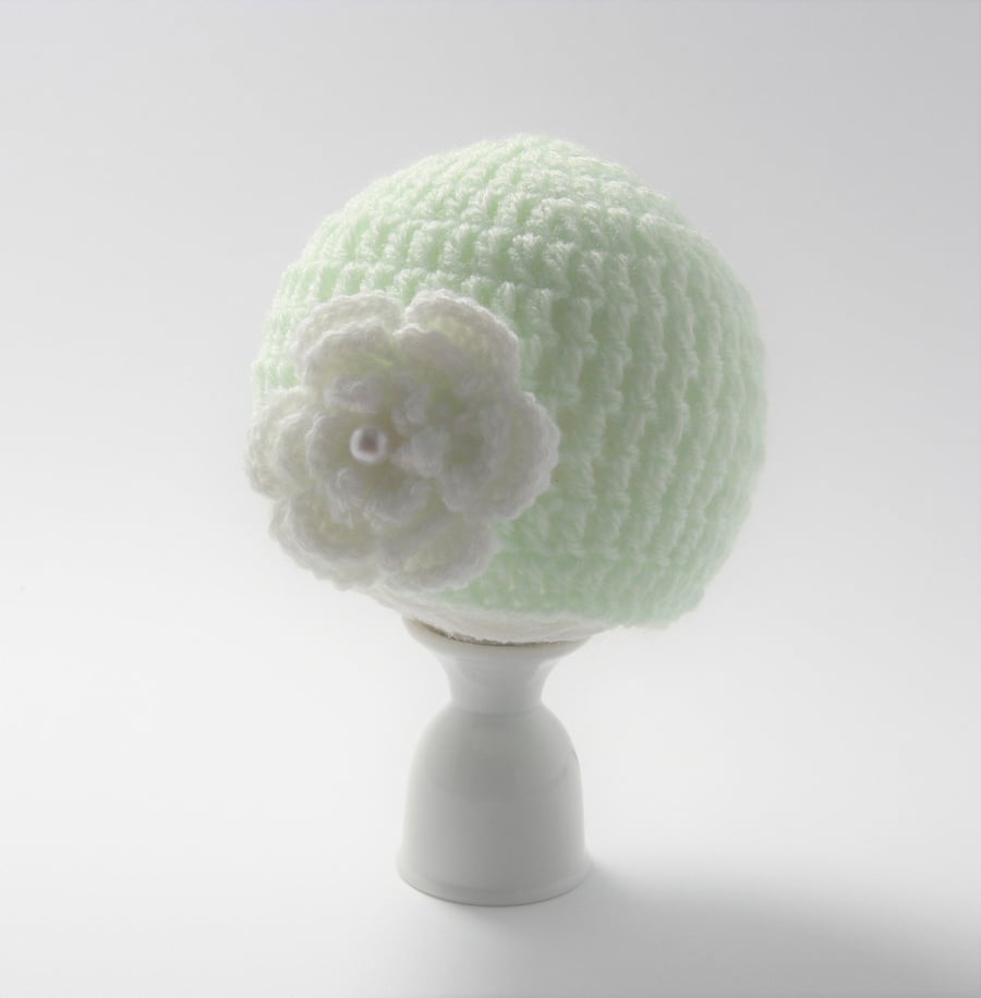 Newborn baby hat in green with a white crochet flower with a pearl attached