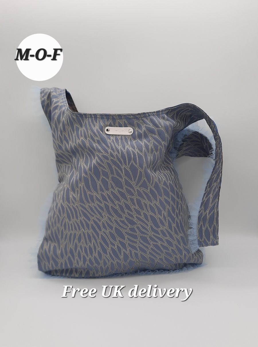 Medium knot bag, reversible shoulder bag in blue with tulle trimming. 