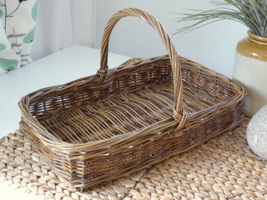A handmade rectangular willow basket with a handle.
