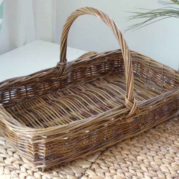 A handmade rectangular willow basket with a handle.