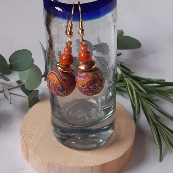 Handmade dangly polymer clay earrings in an orange swirl  design