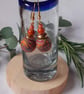 Handmade dangly polymer clay earrings in an orange swirl  design