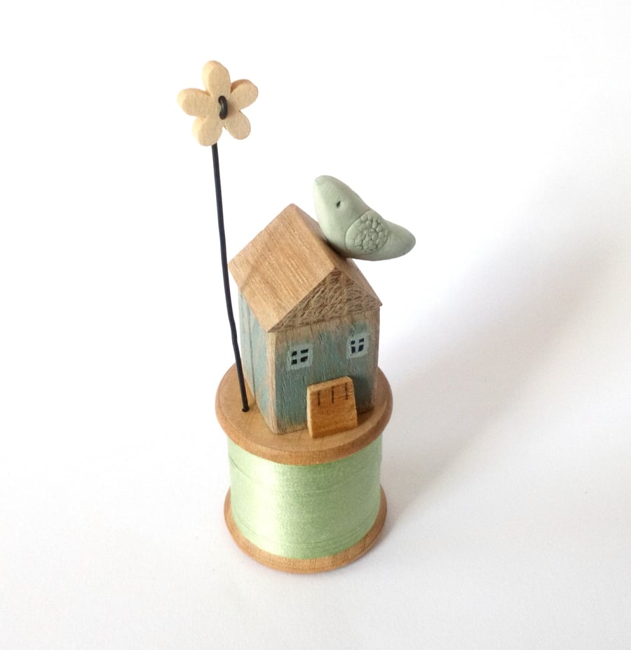Little oak house with clay bird on vintage wooden bobbin