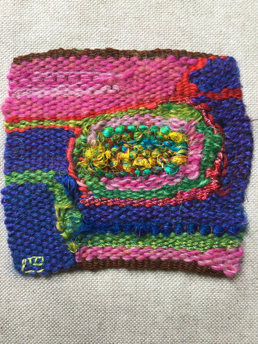 Unframed handwoven tapestry weaving, textile spiral in blue, pink, red and green