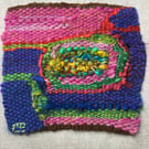 Unframed handwoven tapestry weaving, textile spiral in blue, pink, red and green