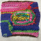 Unframed handwoven tapestry weaving, textile spiral in blue, pink, red and green