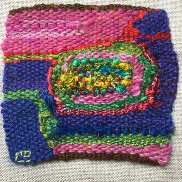 Unframed handwoven tapestry weaving, textile spiral in blue, pink, red and green