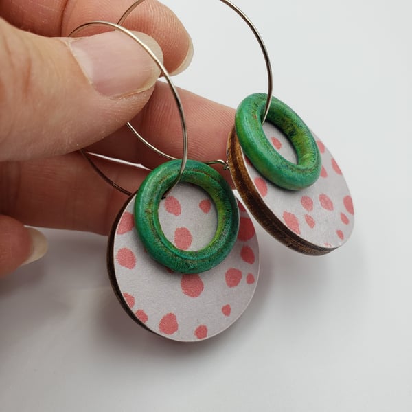 Pink dotty earrings on a grey background with a green hoop beads