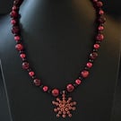 Beaded necklace with a flower charm.