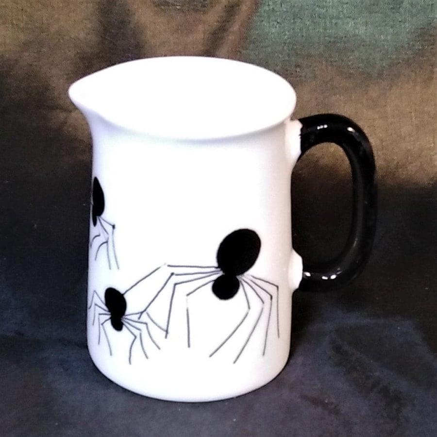 Spiders crawling over a small white bone china milk or water jug or pitcher. Hol