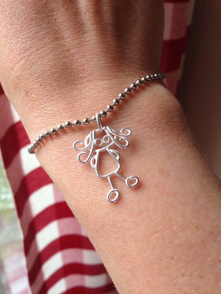 A tiny silver charm from a childs drawing.