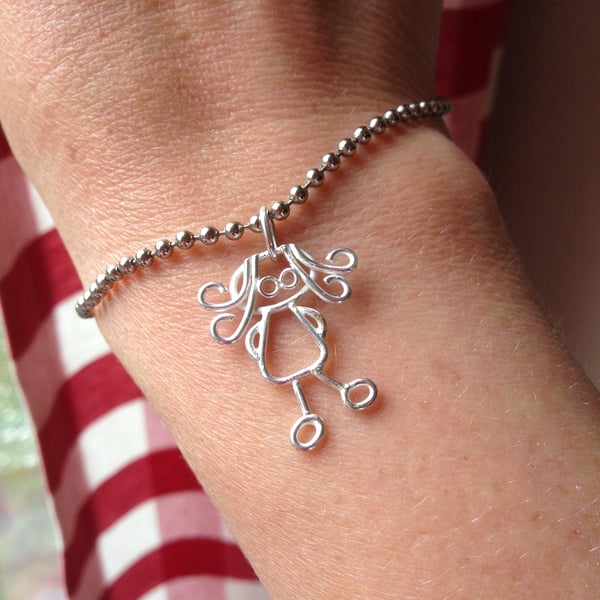 A tiny silver charm from a childs drawing.