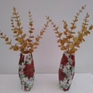 Pair of small decoupaged plastic vases filled with gold Eucaylptus