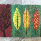 Mounted handwoven tapestry weaving, textile art in red, green, orange and yellow