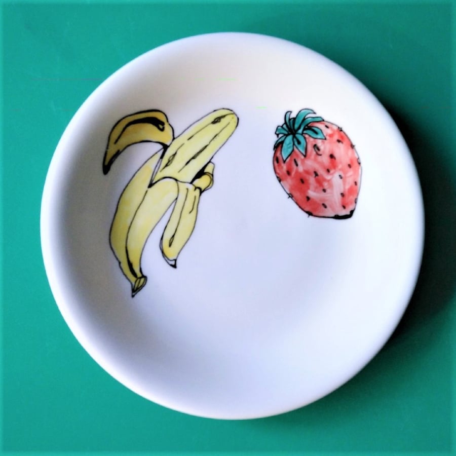 Small shallow dish, hand decorated with fruit, a banana and a strawberry.