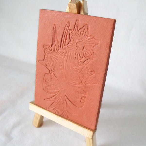 terracotta impressed clay tile displayed on an easel, daffodil design 