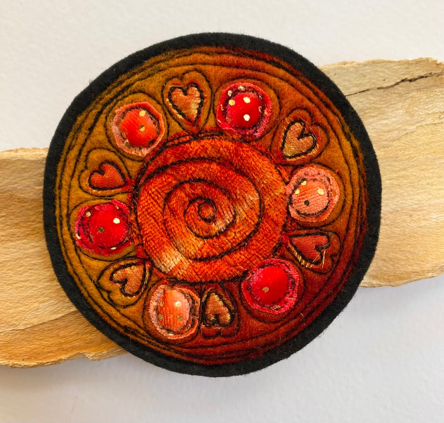 Embroidered circular patterned brooch pin of badge. 