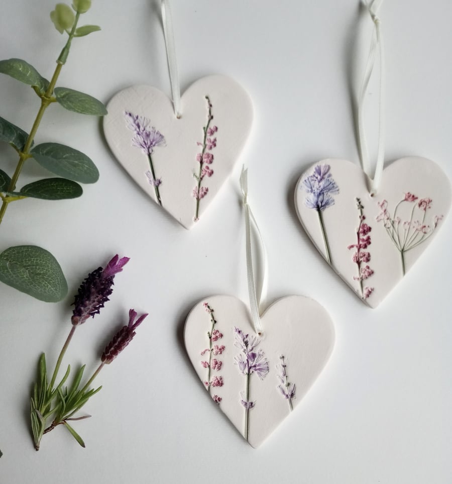 Set of 3 ceramic heart hangings with a botanical print.
