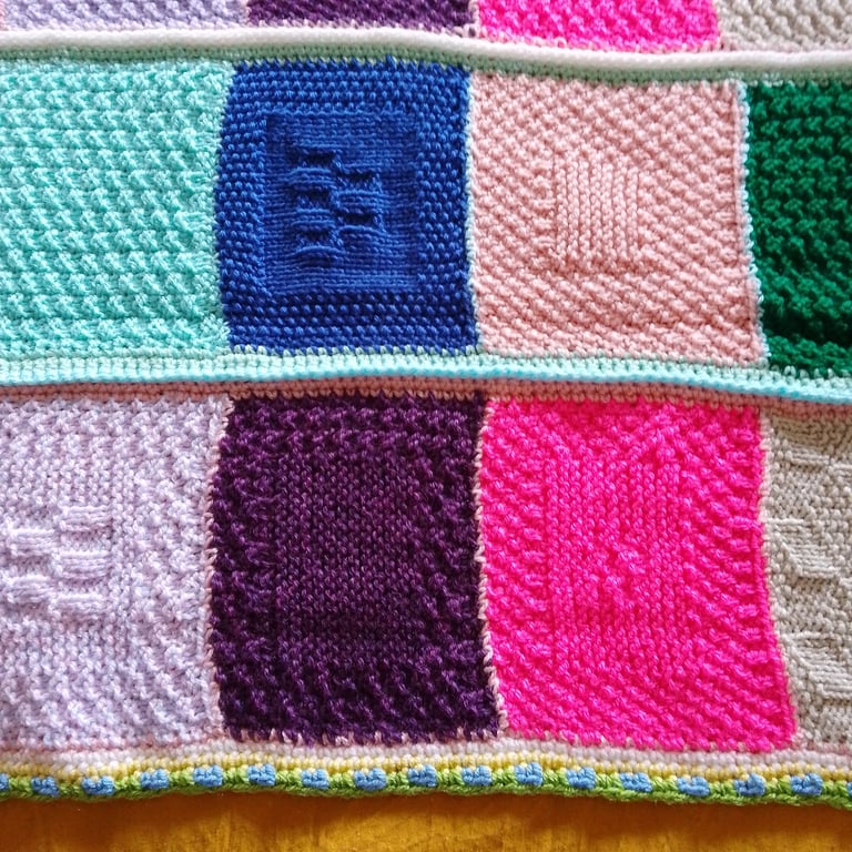 Handmade knitted baby or toddler blanket in a multi coloured theme