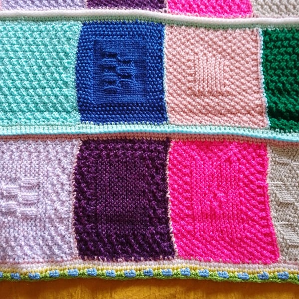 Handmade knitted baby or toddler blanket in a multi coloured theme