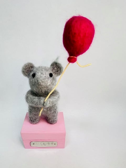 Handcrafted needle felted mouse holding a balloon on a wooden box