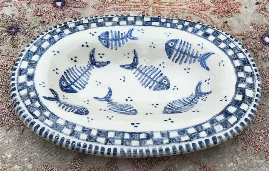 Oval slip ware dish with hand painted fish skeleton design.