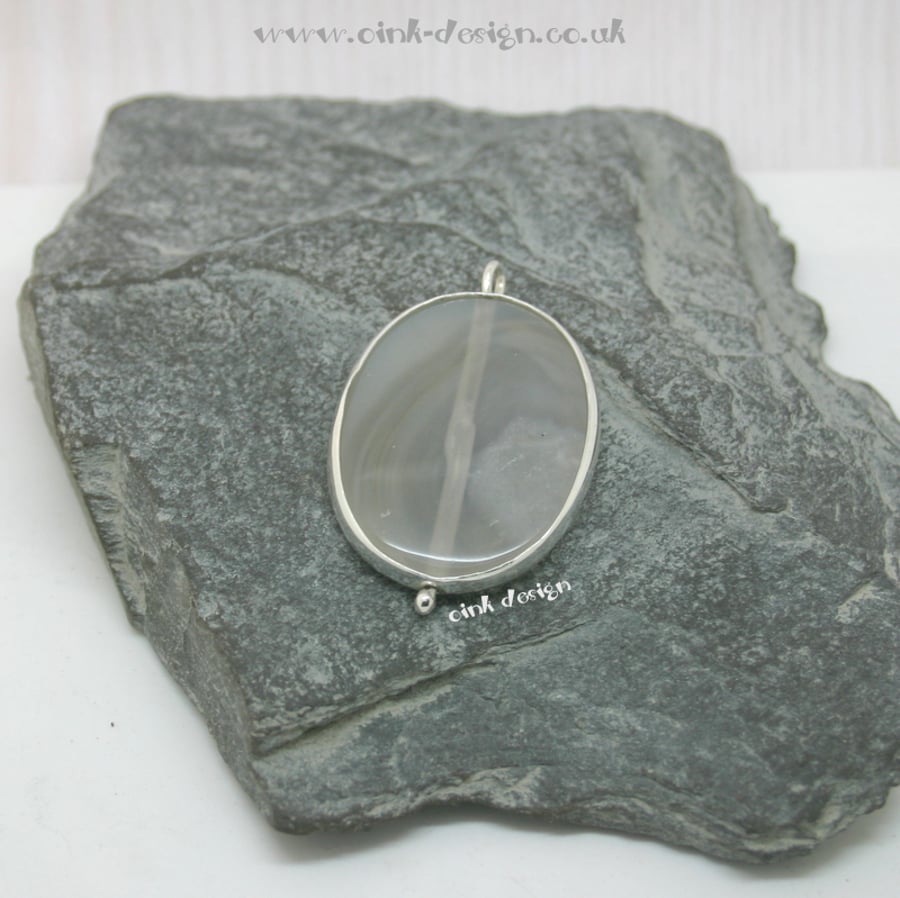 A slice of clear and white agate set in sterling silver spectacle setting