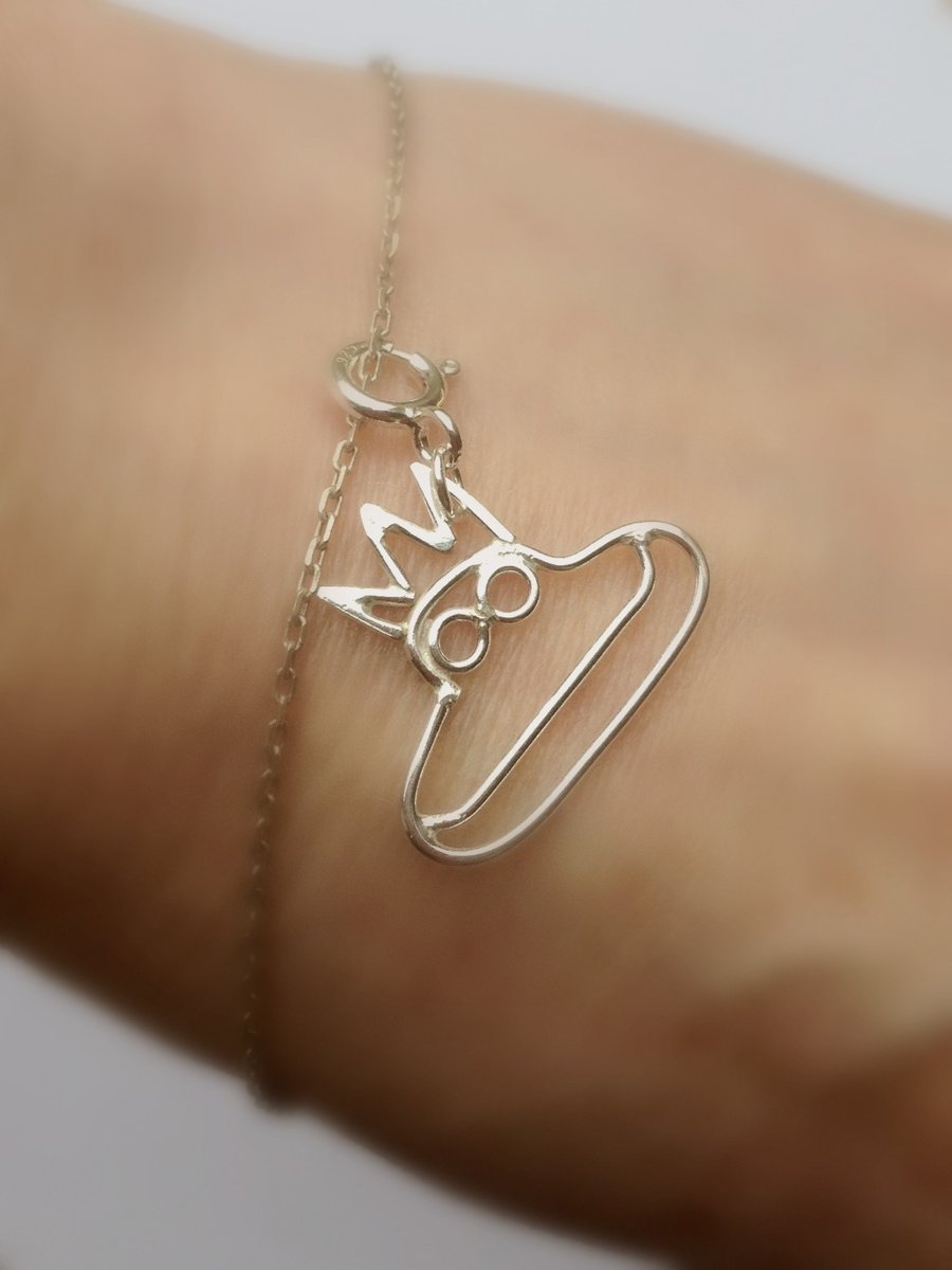 A tiny frog charm made in sterling silver from a childs drawing. 