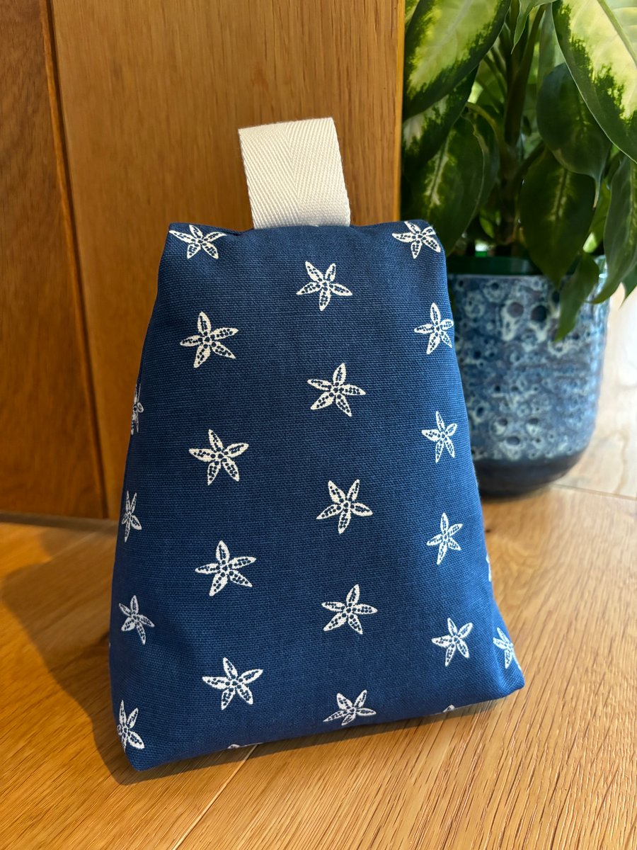 Cotton fabric doorstop in navy with white starfish print, filled with pebbles.