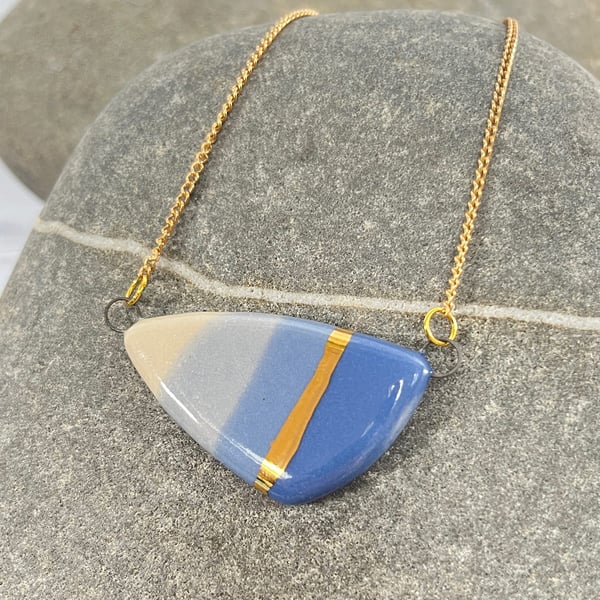 Large pebble shaped pendant in blue tones with 24karat Gold detail