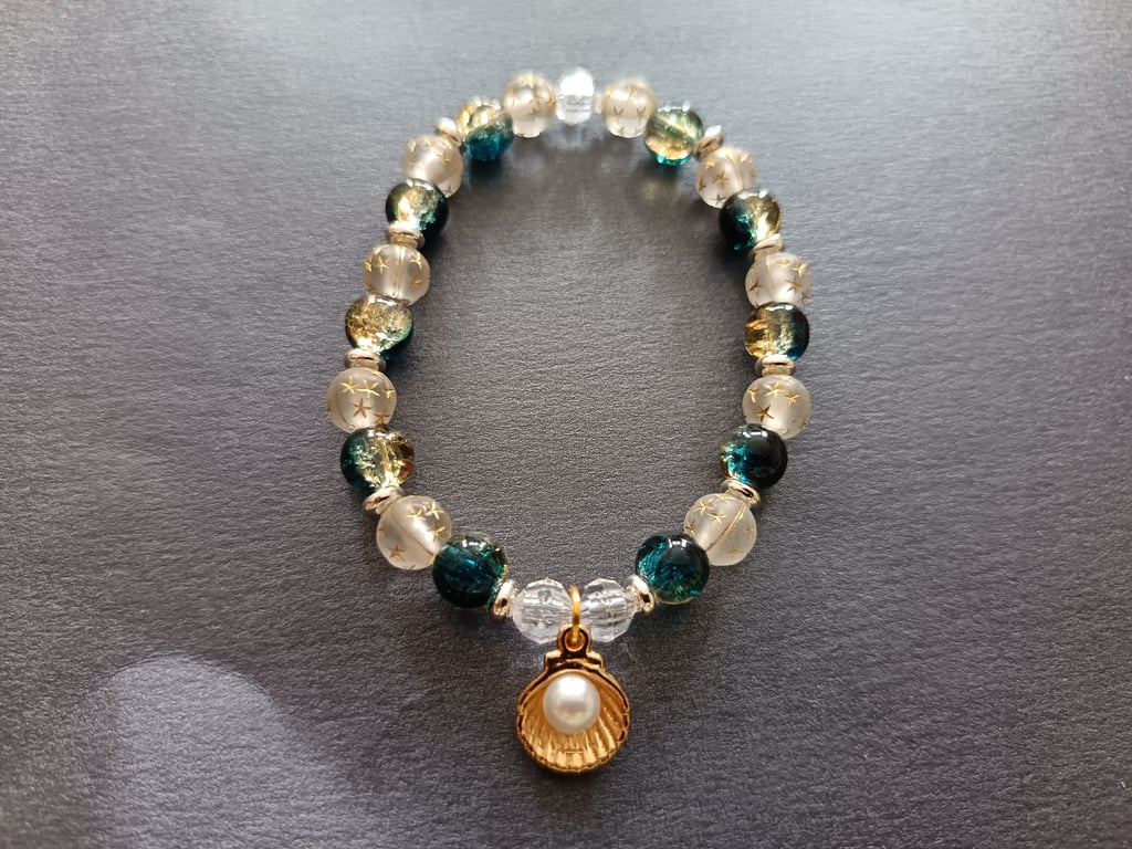 Elasticated bracelet with nautical themed beads and gold shell charm