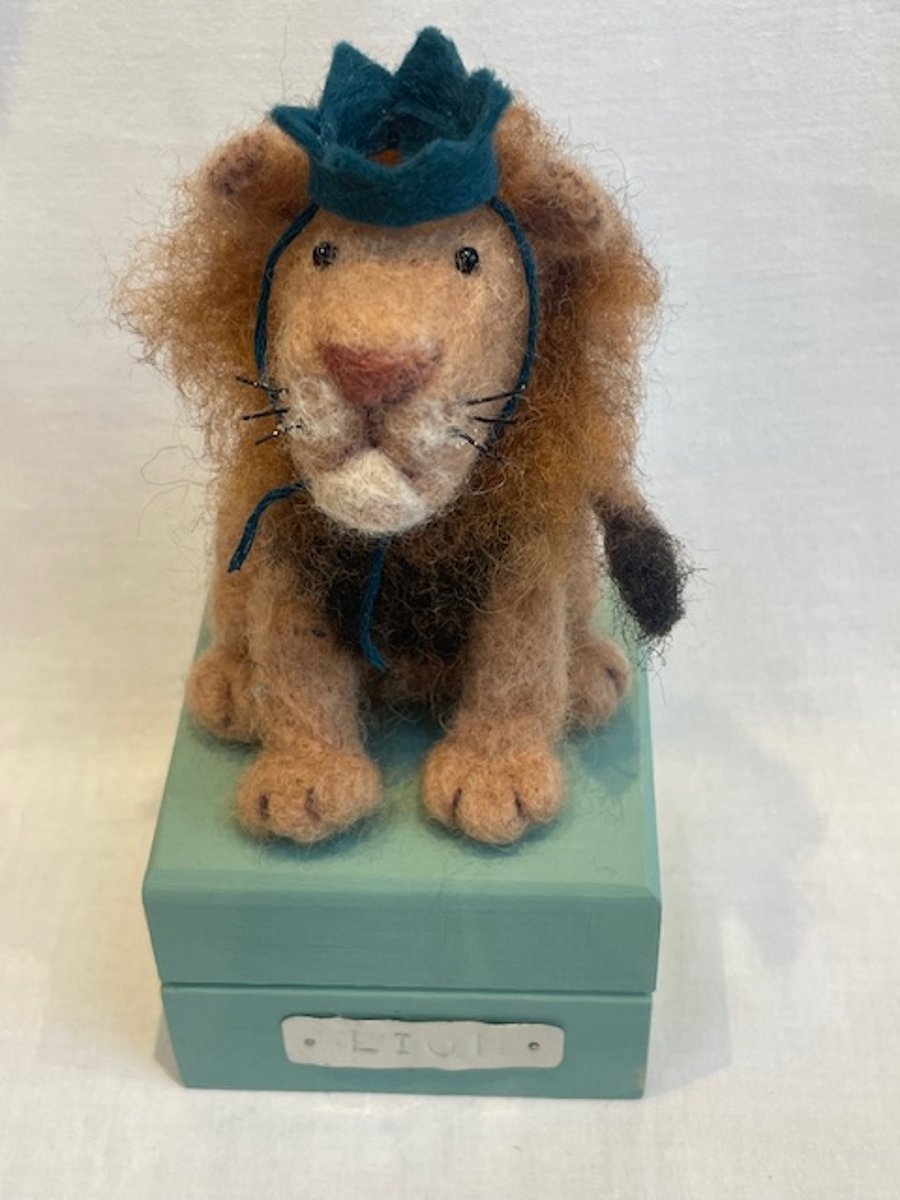Handcrafted needle felted lion with removable party hat on a wooden box
