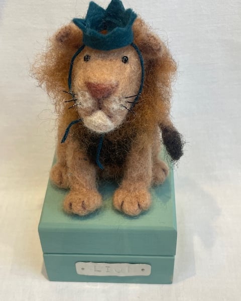 Handcrafted needle felted lion with removable party hat on a wooden box