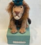 Handcrafted needle felted lion with removable party hat on a wooden box
