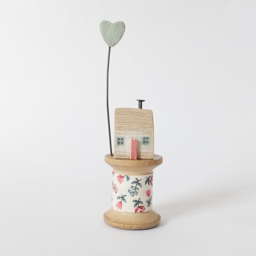 Little wooden house with clay heart on vintage bobbin