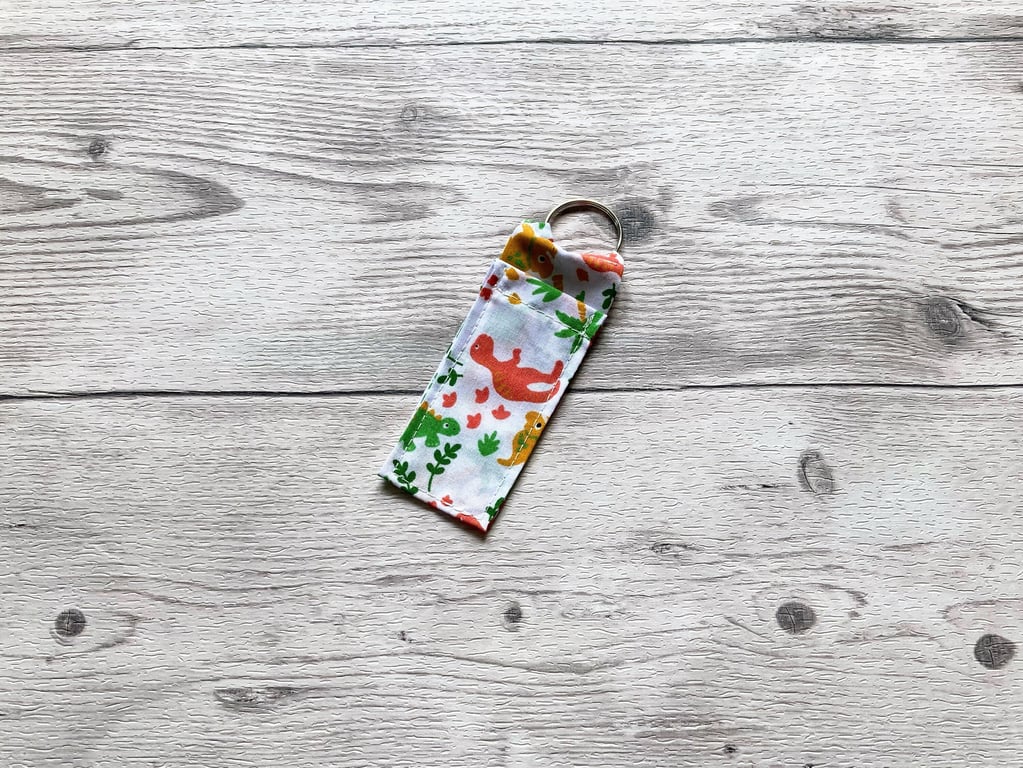 Dinosaur lip balm white polycotton fabric keyring.