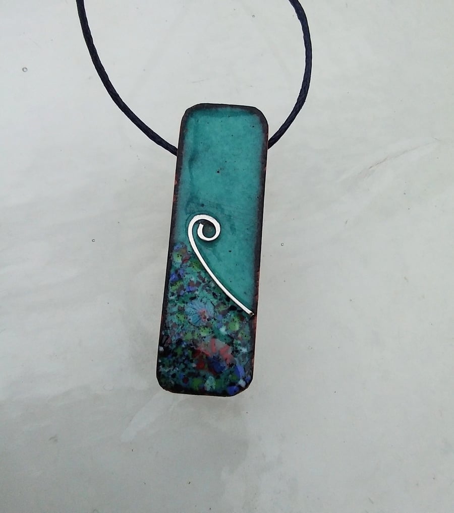 SMALL, SLIM, OBLONG FLORAL ENAMELLED PENDANT WITH STERLING SILVER DESIGN