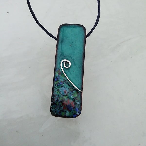 SMALL, SLIM, OBLONG FLORAL ENAMELLED PENDANT WITH STERLING SILVER DESIGN