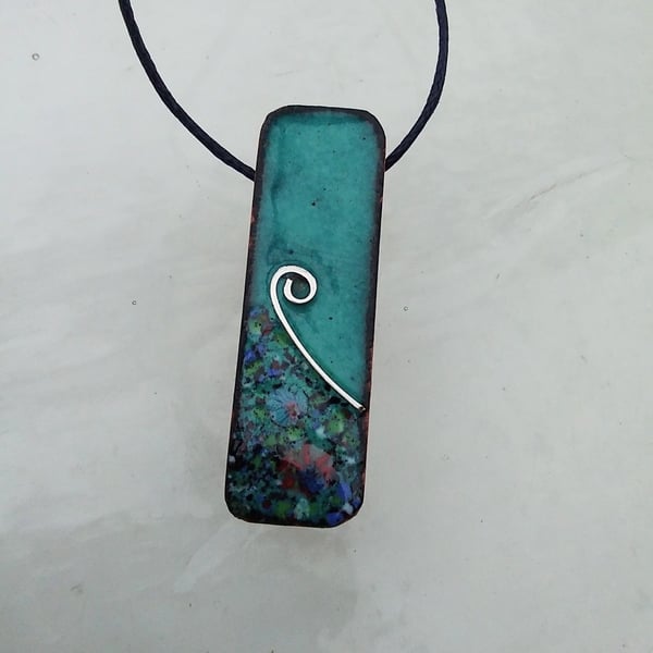 SMALL, SLIM, OBLONG FLORAL ENAMELLED PENDANT WITH STERLING SILVER DESIGN