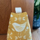 Cotton fabric doorstop in ochre with white bird print, filled with pebbles.