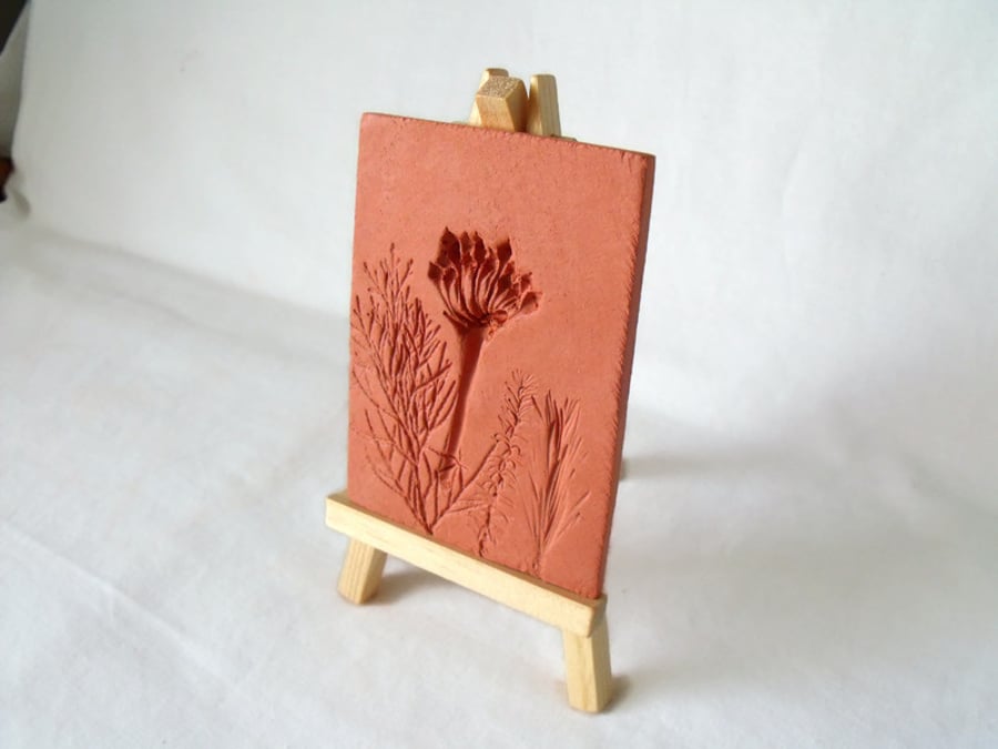 terracotta impressed clay tile displayed on an easel, number 1 of 8 available