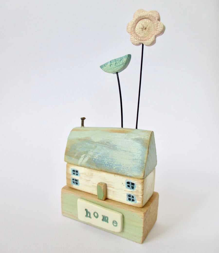 Little wooden home with two clay flowers