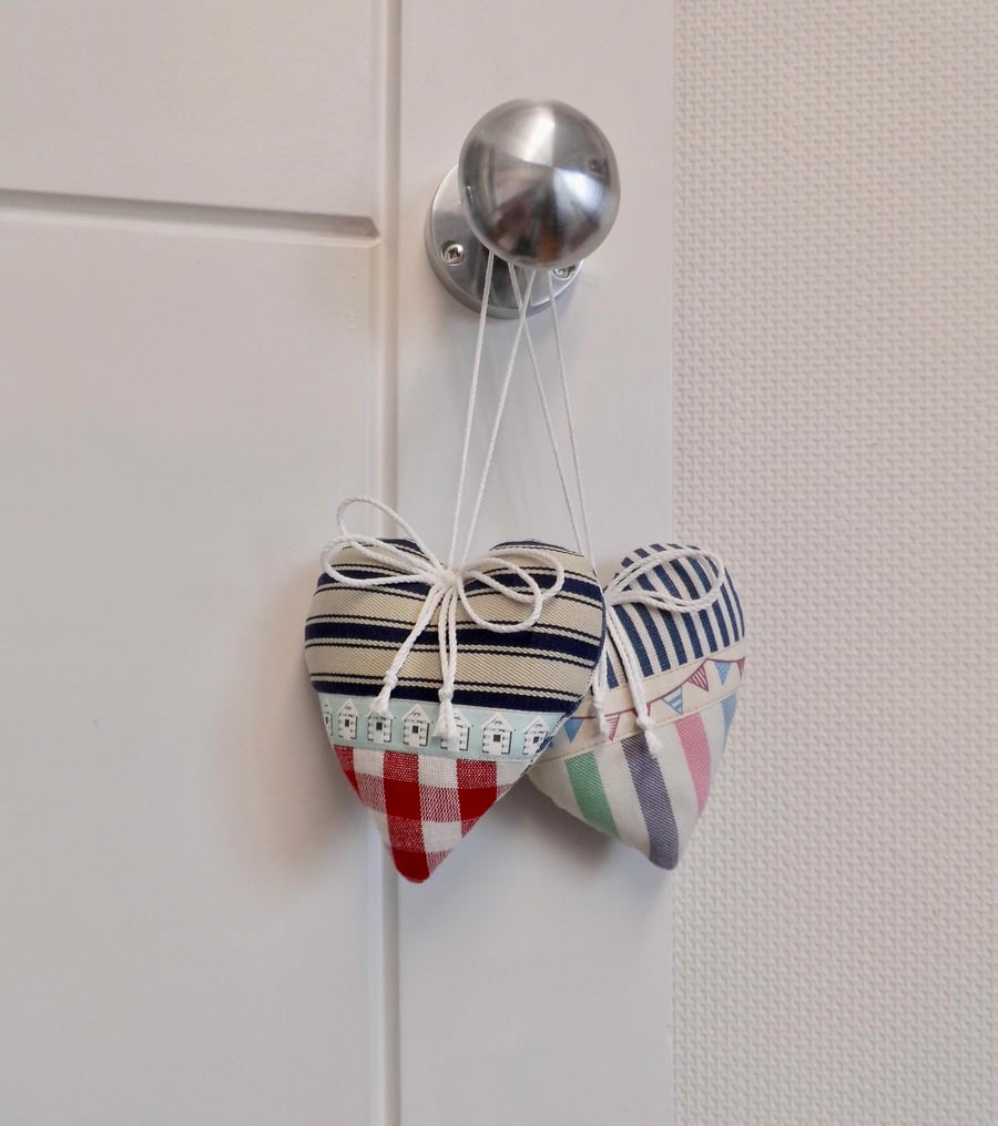 Pair hanging heart decorations on a seaside theme