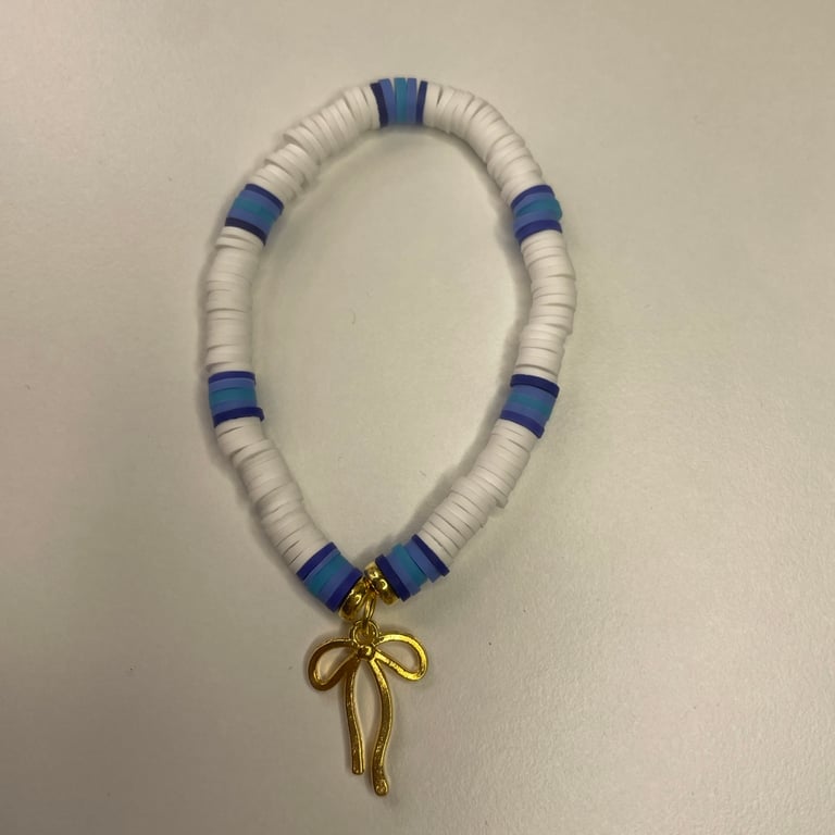 a cute clay bead bracelet with white, a few shades of blue & a golden bow charm!