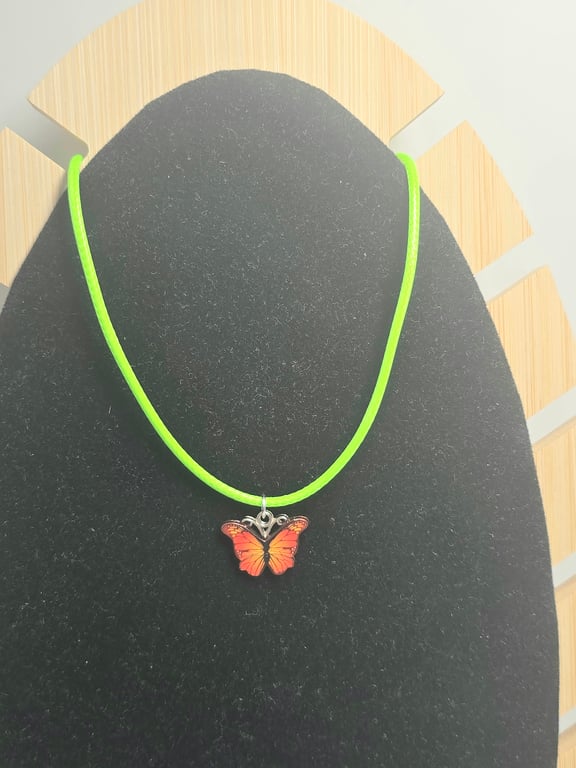 Kids orange butterfly charm necklace on a lime green wax cord 