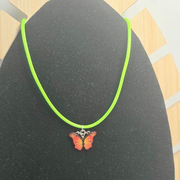 Kids orange butterfly charm necklace on a lime green wax cord 