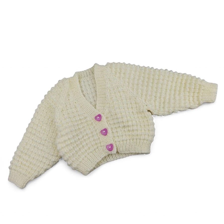 Hand knitted baby cardigan in cream with textured pattern and mauve heart button