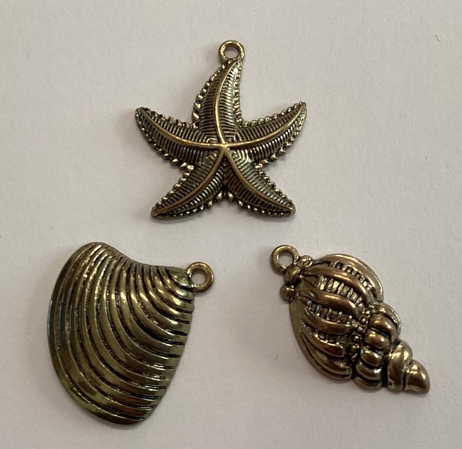 Charms, three brass coloured metal star fish and two shells