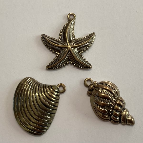 Charms, three brass coloured metal star fish and two shells