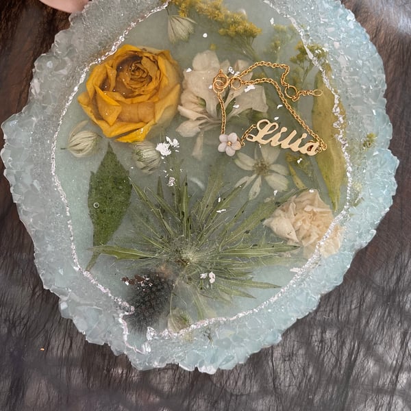Handmade resin coaster with yellow and white dried flowers and a little of silv 